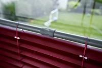 Nahaufnahme einer roten Jalousie mit grauer Halterung